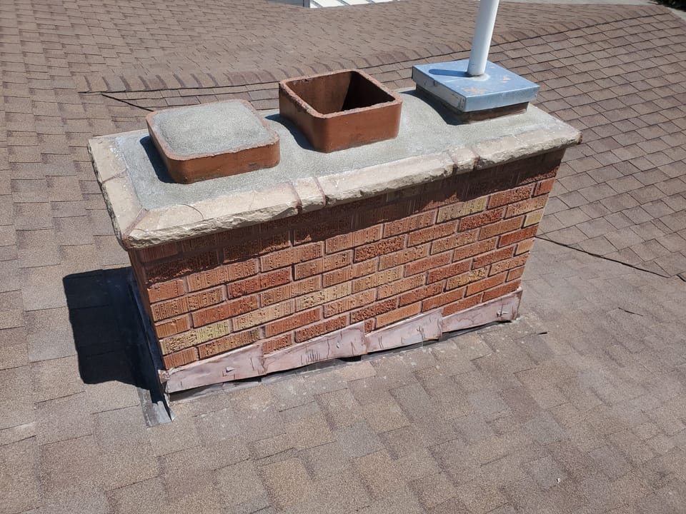 Rebuilt brick chimney with a new cast crown, clay flue tile and fresh flashing at the roofline
