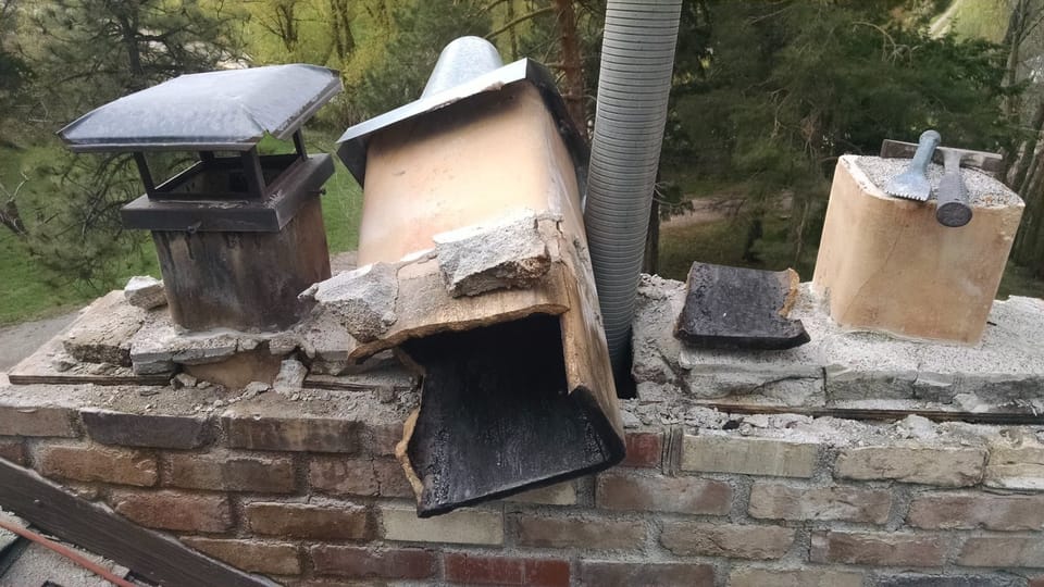 Weathered clay flue liner and removed crown on the chimney top, chisels resting alongside