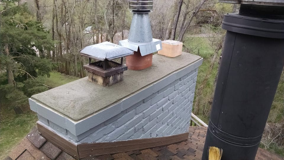 Rebuilt chimney with new concrete crown, drip edge and new top liner section above a shingled roof