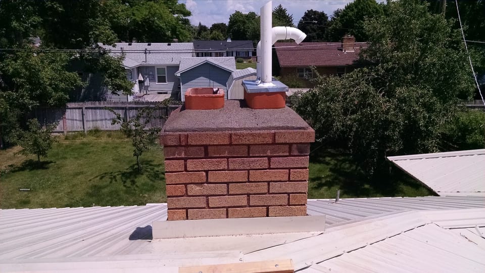 Rebuilt chimney top with a new sloped crown, drip edge and repaired top liner section above the metal roof
