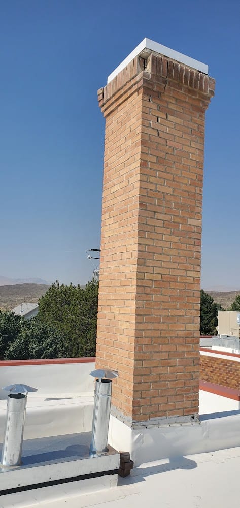 Tall brick chimney with a corbelled crown on the white flat roof of the Owyhee County Courthouse, Murphy, Idaho
